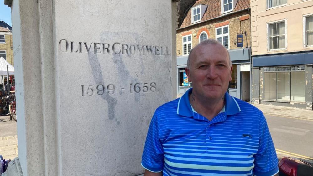 David Cook next to statue plinth