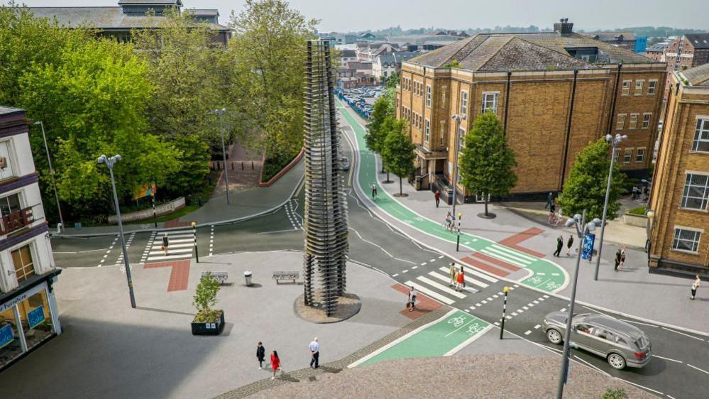 A digital image of Gloucester city centre showing green segregated cycle lanes crossing a main road alongside a zebra crossing