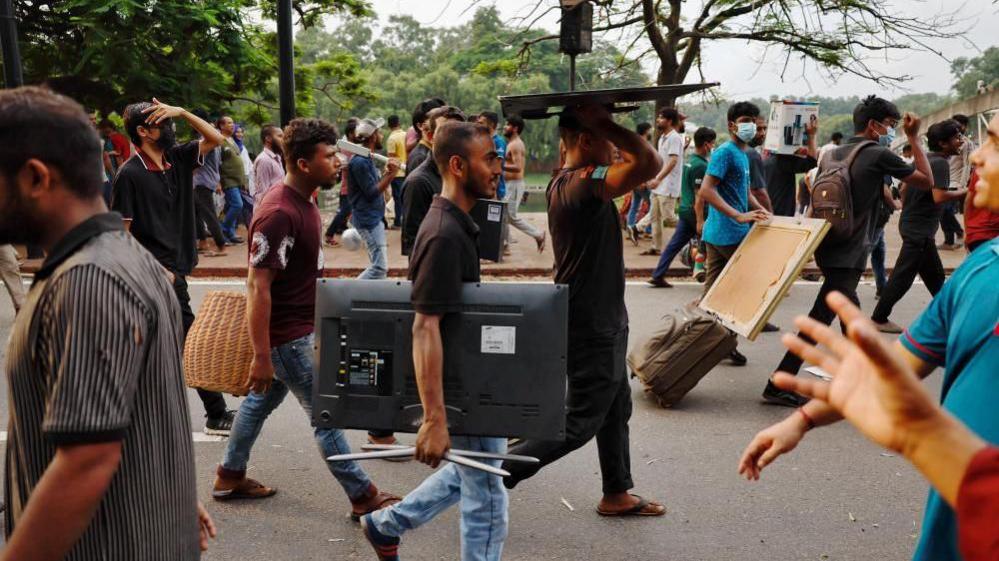 People carry looted items from the Ganabhaban, the Prime Minister's residence