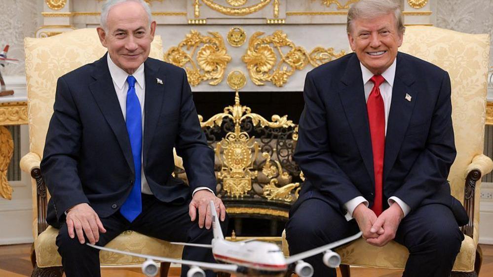 Netanyahu and Trump smile towards the camera during their meeting at the White House