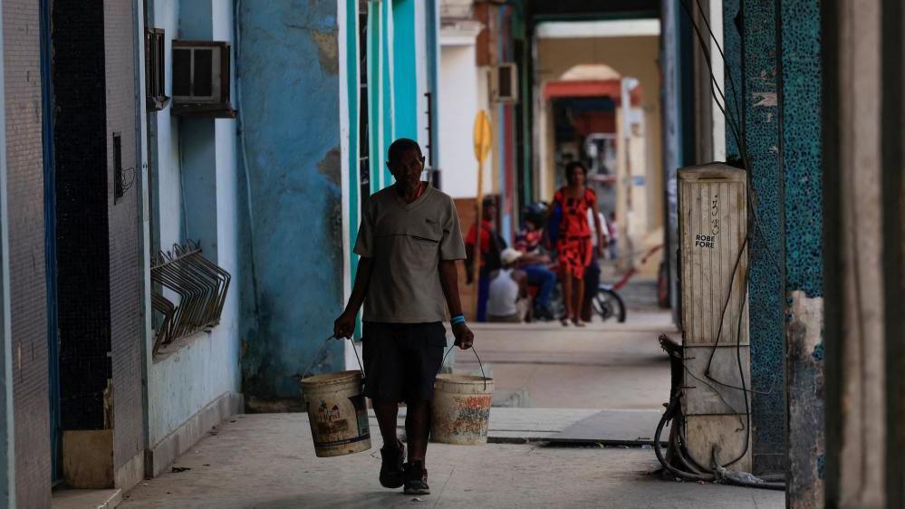 man carries paint buckets with water ahead of an announcement by Cuba's grid operator UNE that it had reconnected most of the country to the national grid, though millions remained without power as the country struggles to generate even one-third of current demand amid an ongoing U.S. fuel blockade, in Havana, Cuba, July 7, 2026. R man carries paint buckets with water ahead of an announcement by Cuba's grid operator UNE that it had reconnected most of the country to the national grid, though millions remained without power as the country struggles to generate even one-third of current demand amid an ongoing U.S. fuel blockade, in Havana, Cuba, July 7, 2026. REUTERS/Norlys Perez