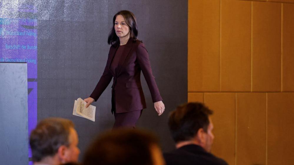 German Foreign Minister Annalena Baerbock arrives for a press conference in China wearing a purple suit and carrying her papers