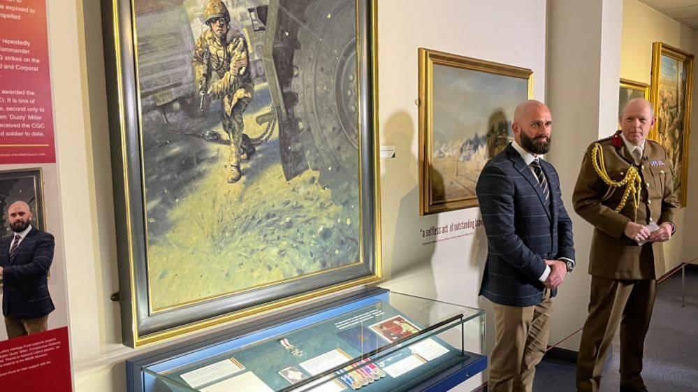 Corporal Adam Miller standing next to his medals