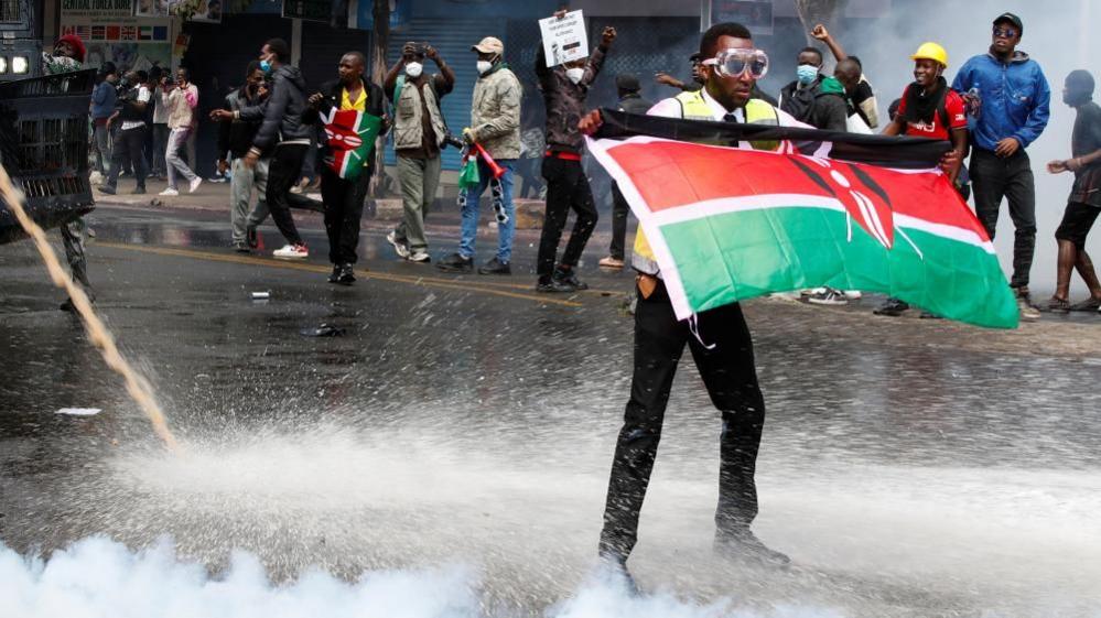 A demonstrator holds a Kenyan flag as police use water cannons and tear gas to disperse protesters during a demonstration against Kenya's proposed finance bill 2024/2025 in Nairobi, Kenya, June 25, 2024.