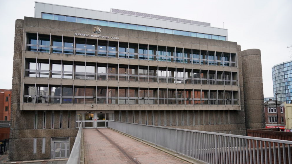 Exterior view of entrance to Sheffield Magistrates' Court showing a footbridge leading to a Brutalist concrete and glass building