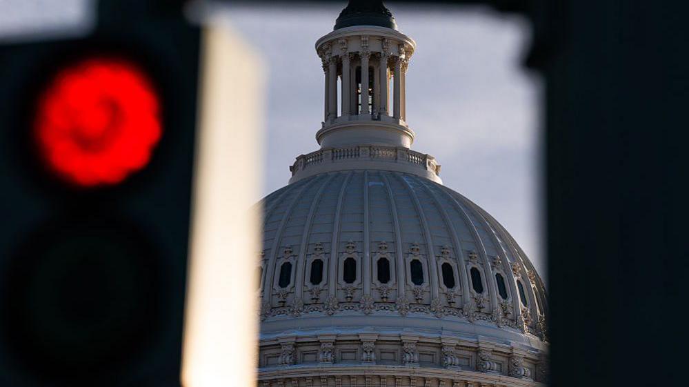 A red street light seen next to the US Capitol Dome at Congress