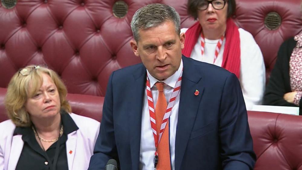 Lord James Timpson speaks in the House of Lords with red benches seen behind him.