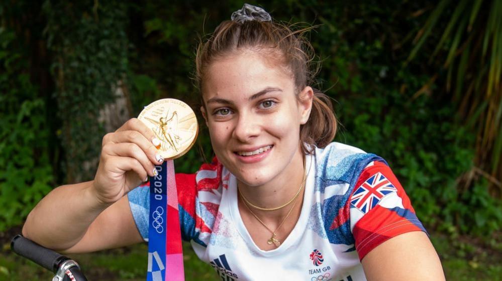 Beth Shriever sat on her BMX and holding up her gold medal