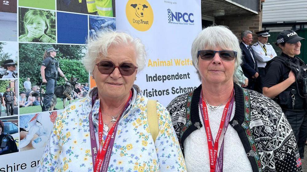 Two women with short grey hair looking at the camera wearing sunglasses