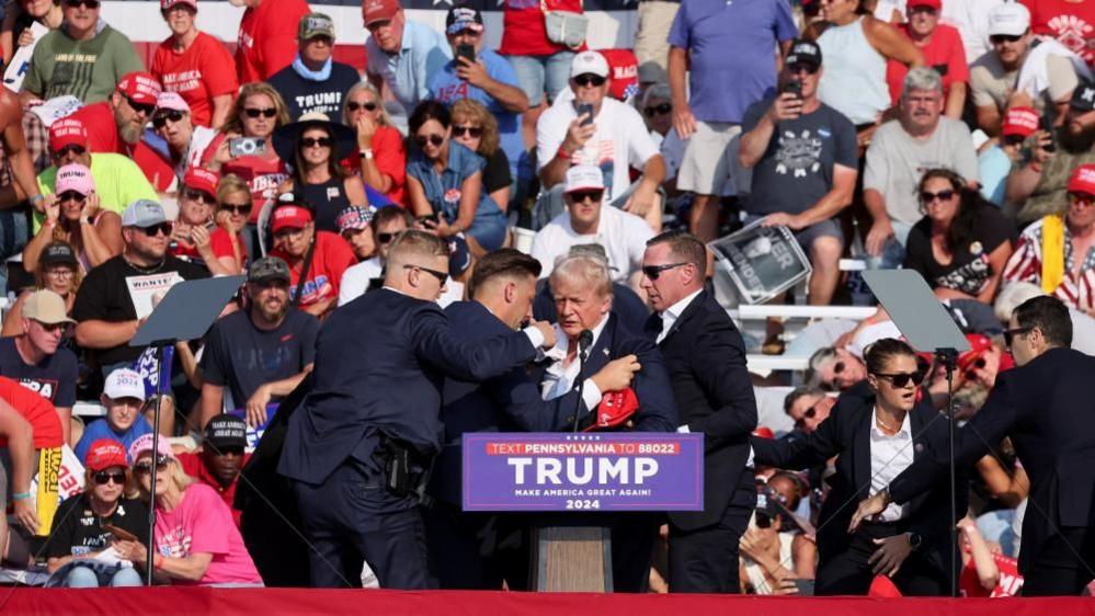 Donald Trump is shielded by Secret Service officers after shooting at rally