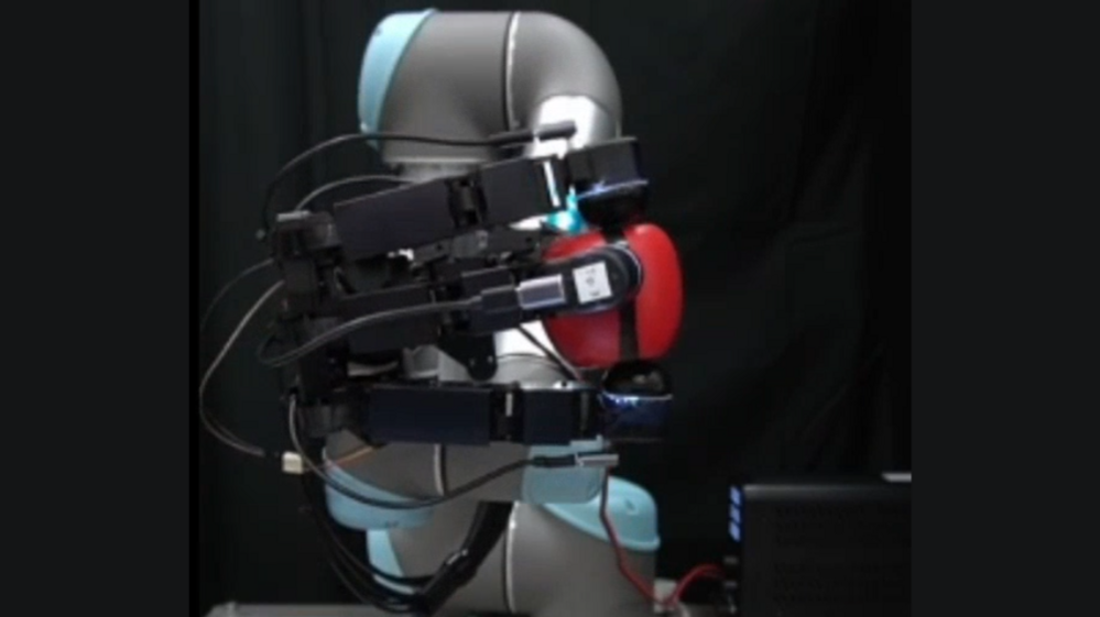 A robotic hand gripping a red plastic apple