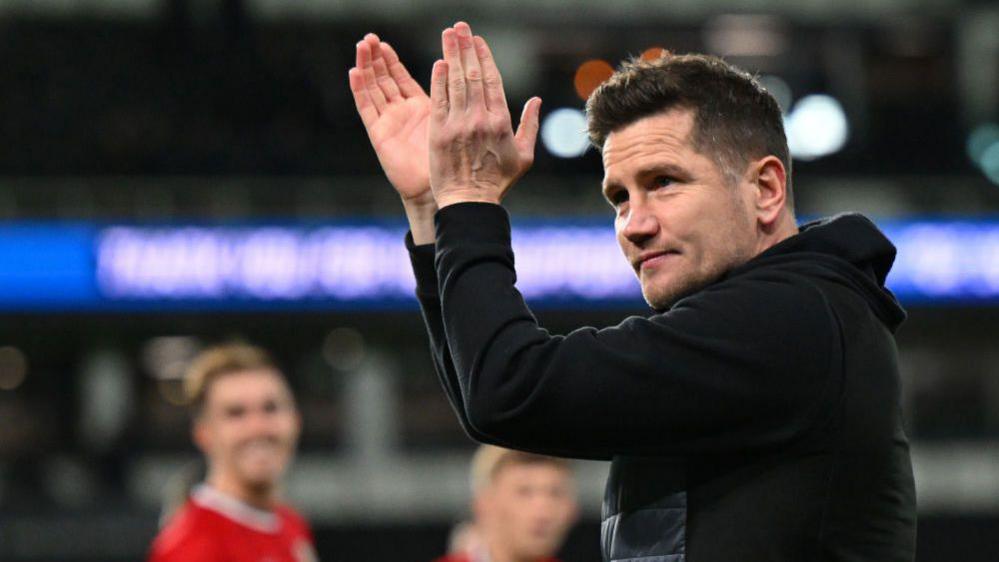 Crewe boss Lee Bell claps the crowd after a match