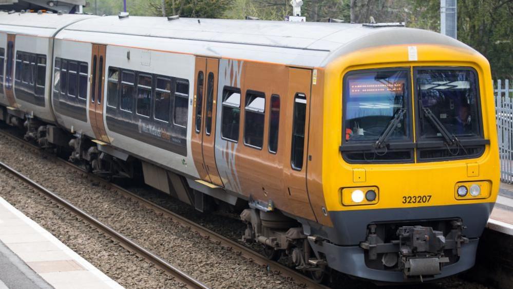 A West Midlands Railway train that is stationary at a platform.