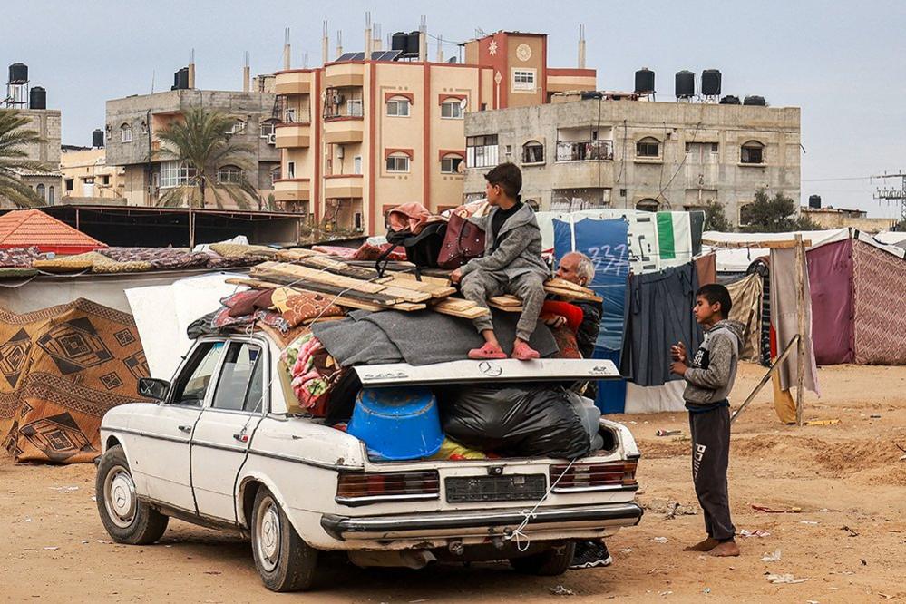 People pack a vehicle before fleeing north towards central Gaza, in Rafah on 13 February