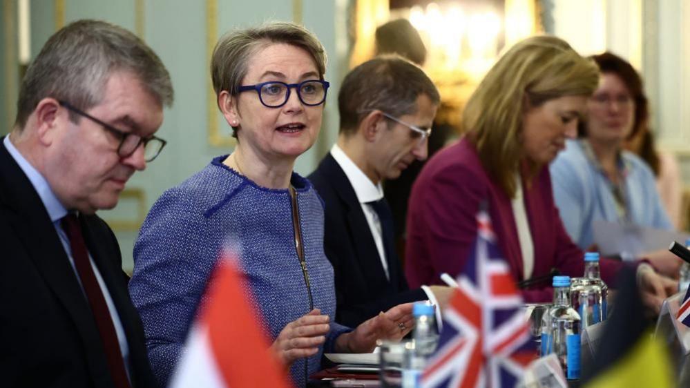 Home Secretary Yvette Cooper sits at a table with a man sat to her left and a man and two women sat to right, during a Calais Group meeting