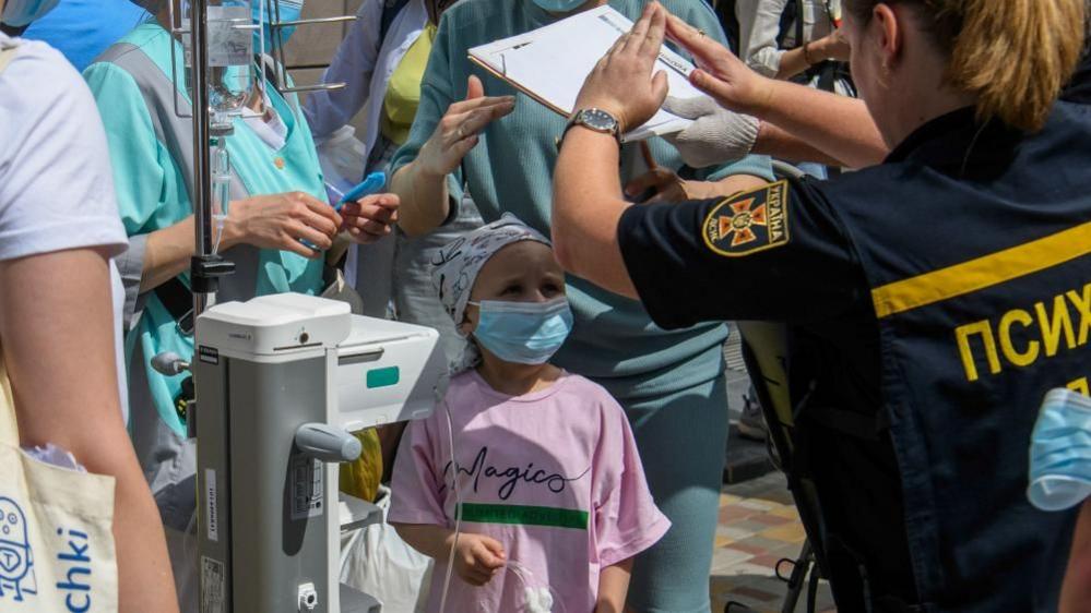 A psychologist gestures to a little girl at the site of a missile strike on the 'Okhmadyt' children's hospital in Kyiv, Ukraine, 08 July 2024, amid the Russian invasion.