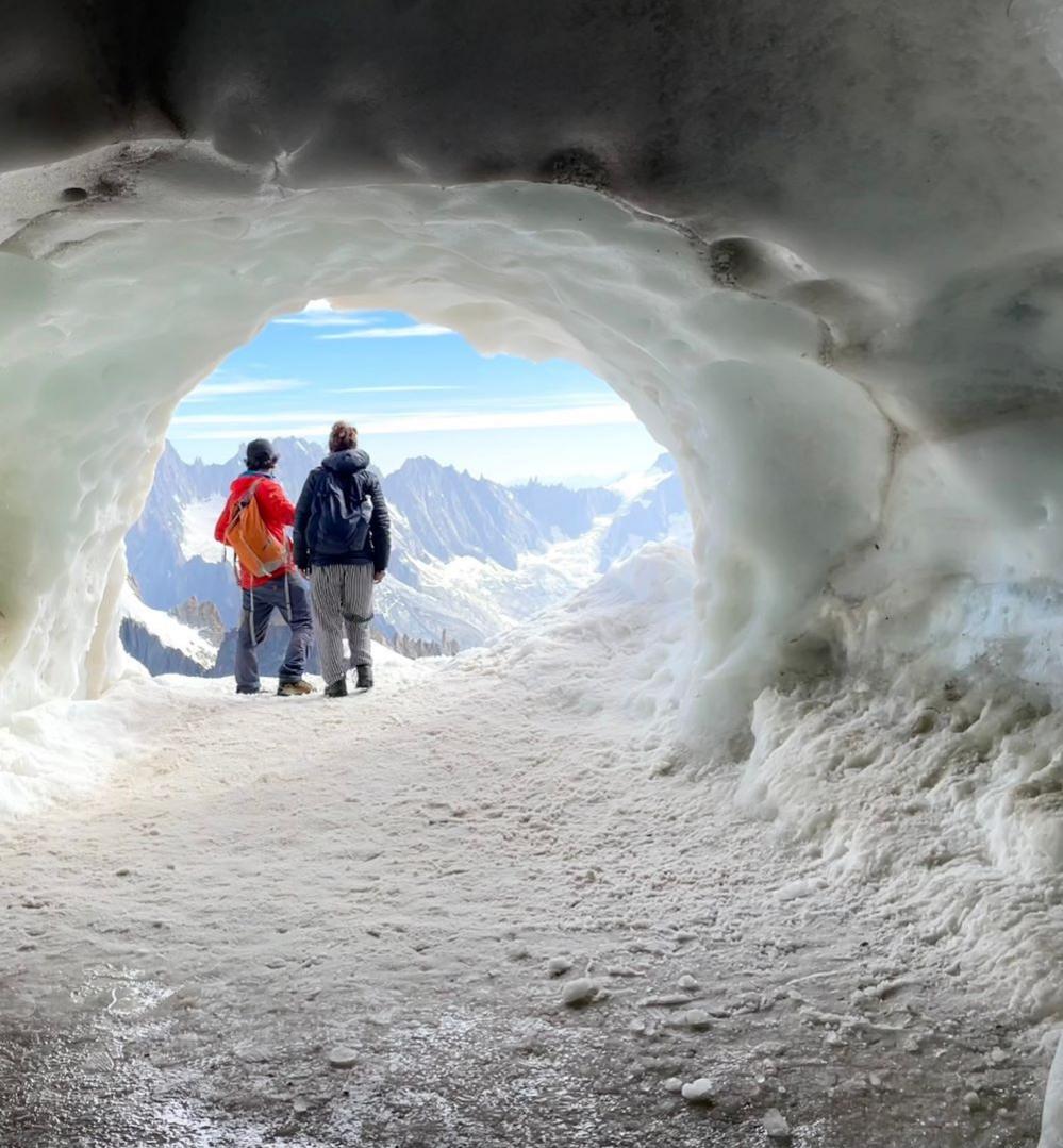 People at the mouth of an ice tunnel in the French Alps