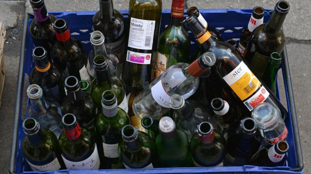 A blue box full of empty wine bottles.