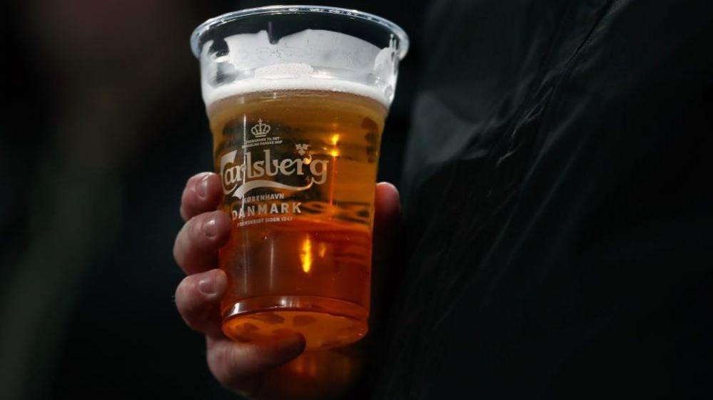 Person holding a pint of Carlsberg beer