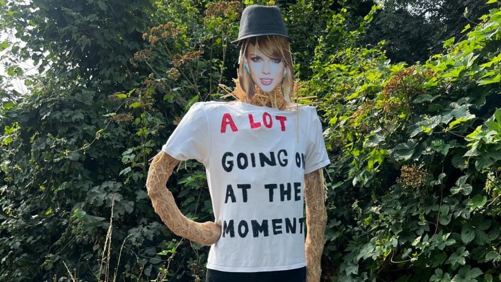 A Taylor Swift scarecrow, with A Lot Going On At the Moment written on her