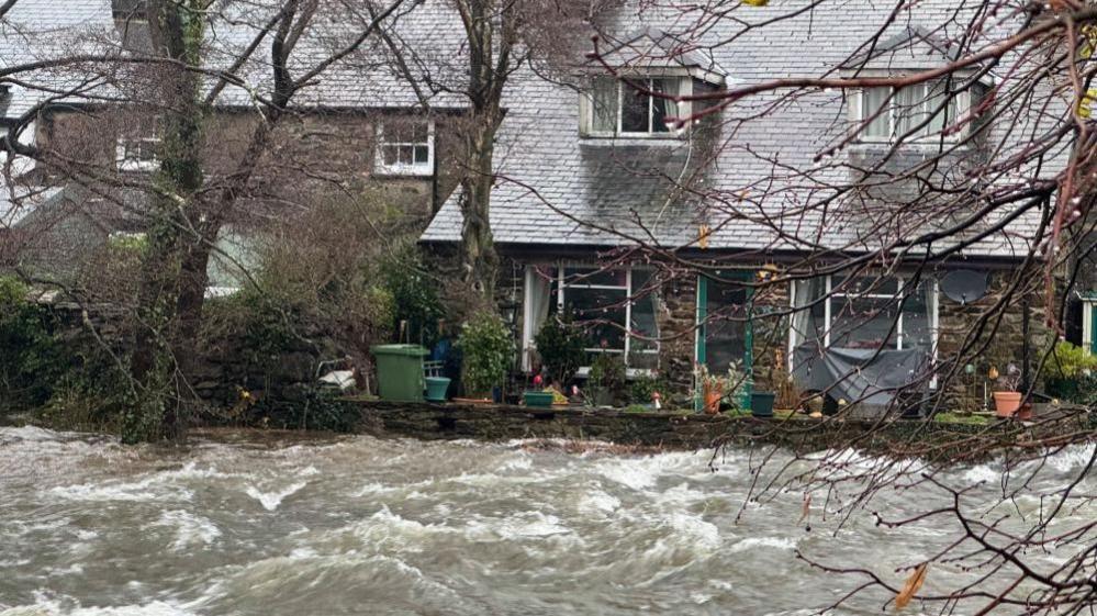 The Afon Glaslyn has risen close to the top of the wall surrounding this house in Beddgelert, Gwynedd