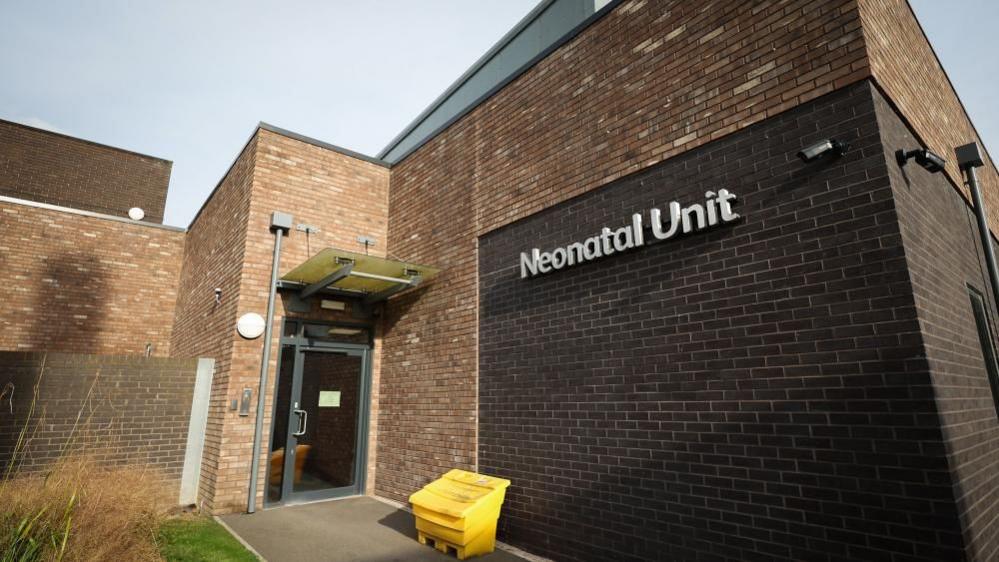 A dark brick building with the words 'neonatal unit' on its side