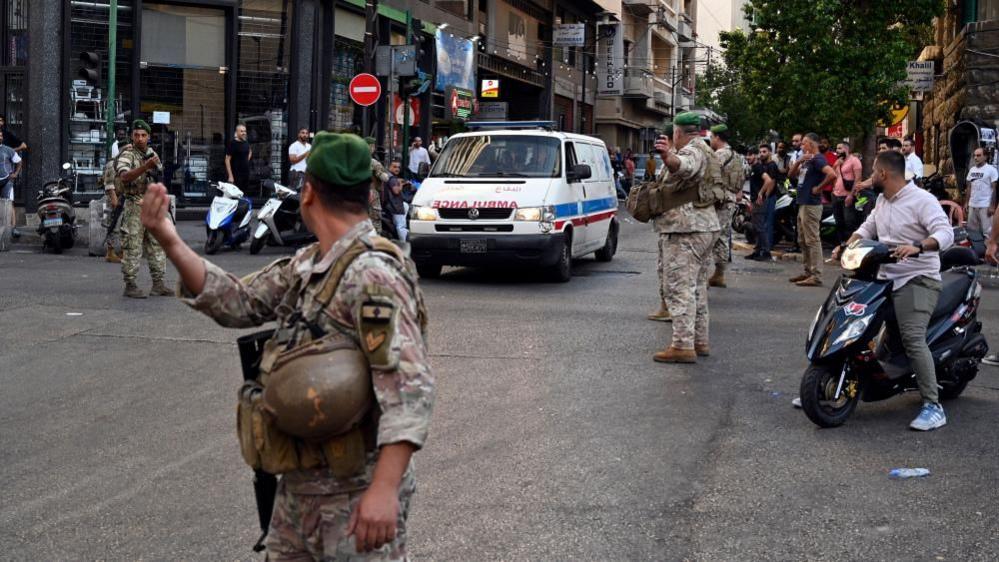 Ambulance arrives at the American University of Beirut Medical Centre with members of public and army surrounding 