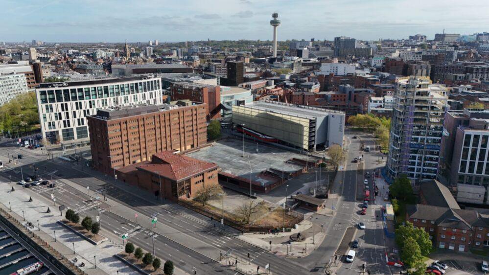 An aerial side view of Canning Place with Liverpool ONE behind and the Strand road running down the right hand side of it. 