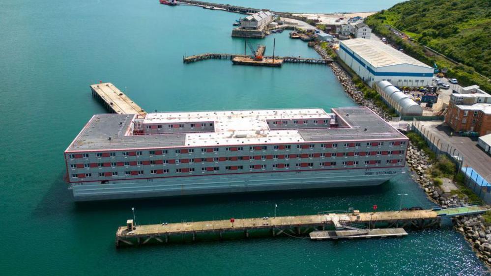 A large red and grey barge docked in the sea in Portland Port