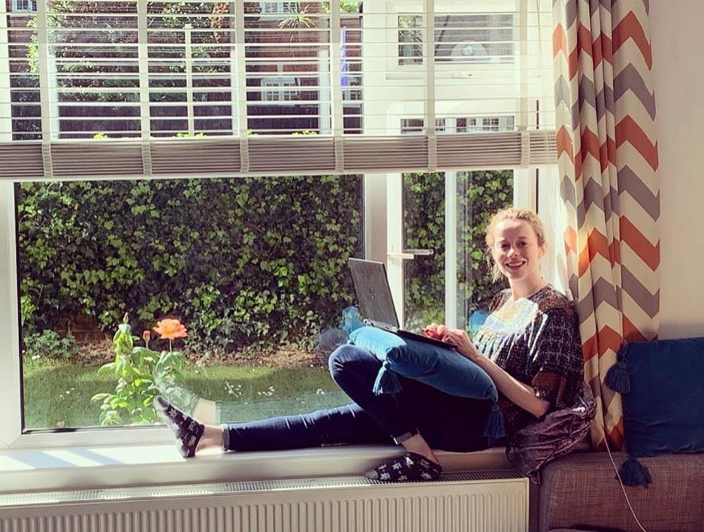 Woman on window sill with a laptop