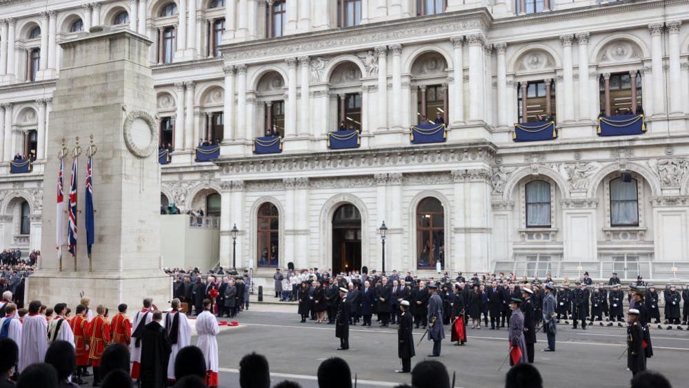 King Charles stands with other royals and politicians, with a large crowd of onlookers as they attend the Remembrance Sunday Service at the Cenotaph in London. 