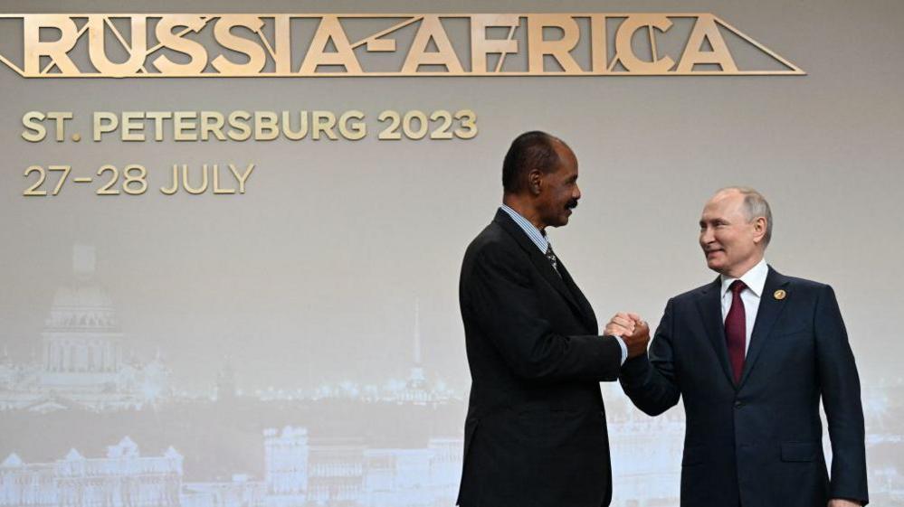 Isaias Afwerki is seen shaking hands with his Russian counterpart, Vladimir Putin. Behind then is a sign that says - Russia-Africa, St Petersburg 2023, 27-28 July