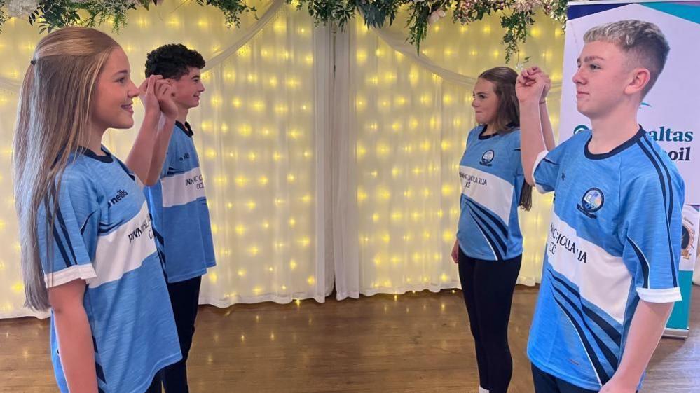 Four children dancing. They are wearing blue tops.