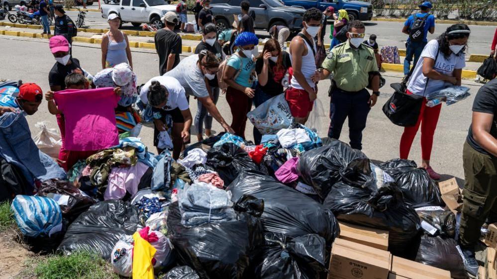People queue for clothing donations on the streets of Caraballeda, in La Guaira state