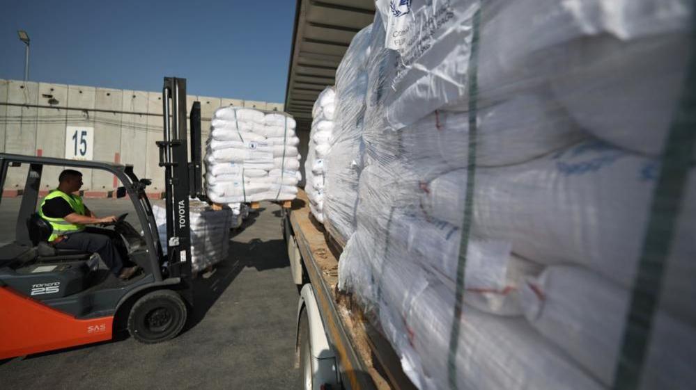 A forklift driver loading pallets of aid onto the back of a lorry