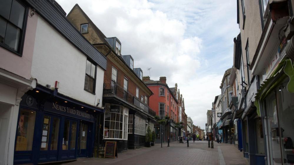 A view up a street in Bury St Edmunds showing old buildings and bow-fronted shop windows