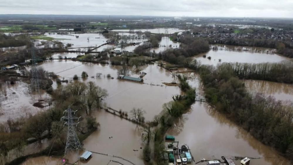 An aerial image of fields submerged in brown floodwater