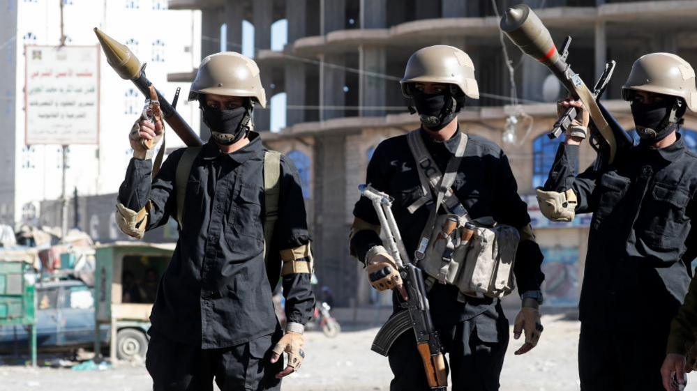 Three Houthi fighters stand guard in Sanaa