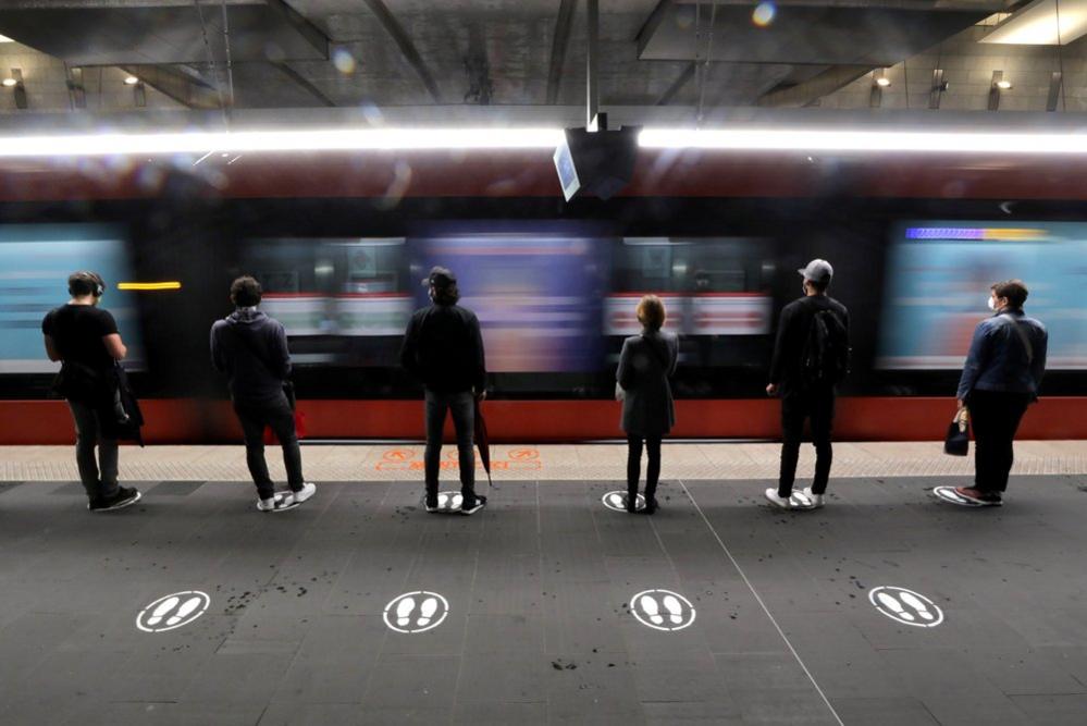 People stand on markers on a tramway platform