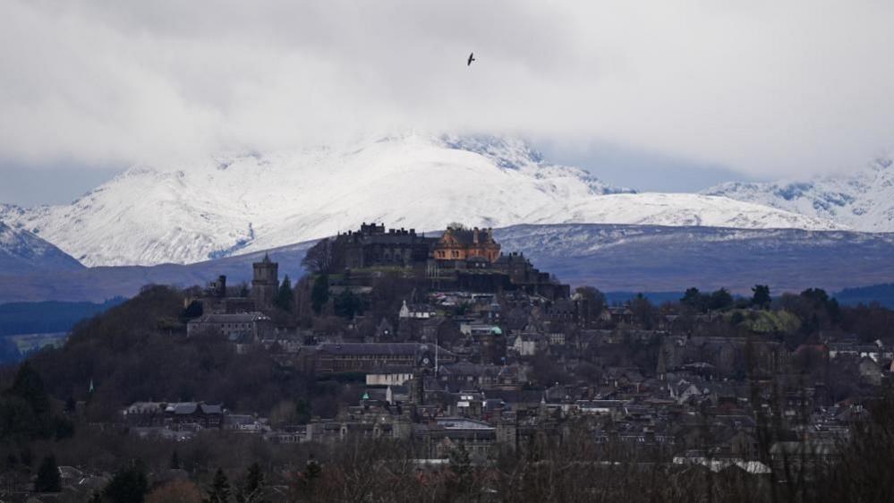 Stirling castle with Stirling city in the foreground and snow covered mountains in the background.