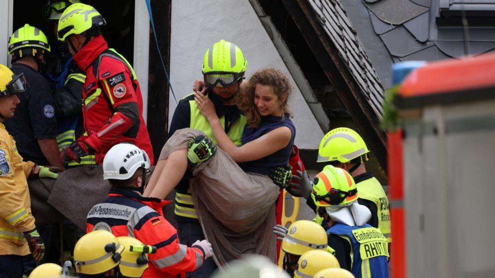 A firefighter carries a woman after a hotel partially collapsed overnight near the banks of Germany's river Moselle in Kroev, Germany, August 7, 2024.