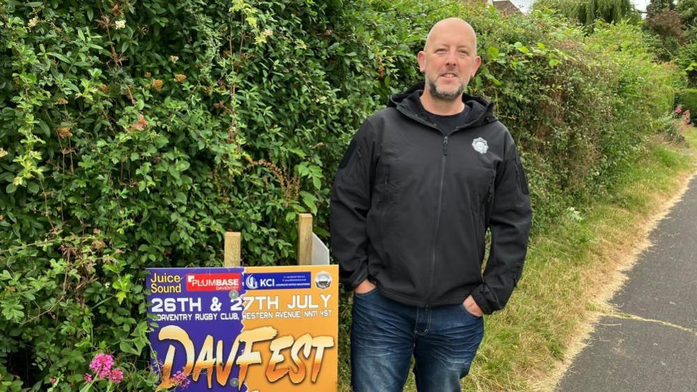 Man in black jacket standing next to sign that's now on private land