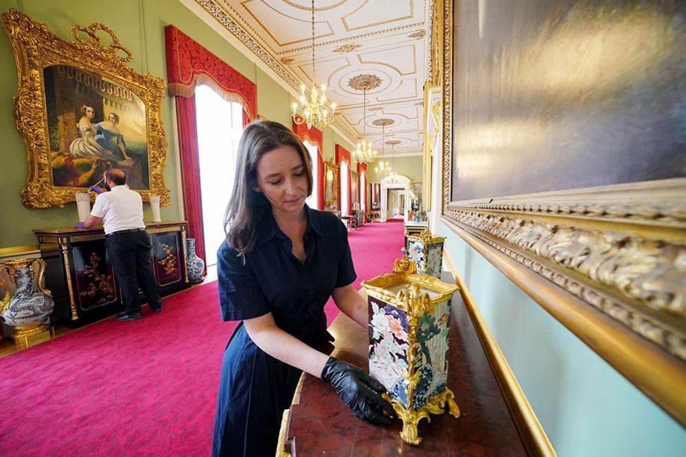 Members of Royal Collection Trust staff tend to objects in the Principal Corridor