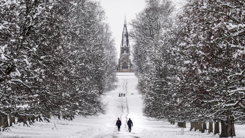 People walking in the snow in Studley Royal park in North Yorkshire.