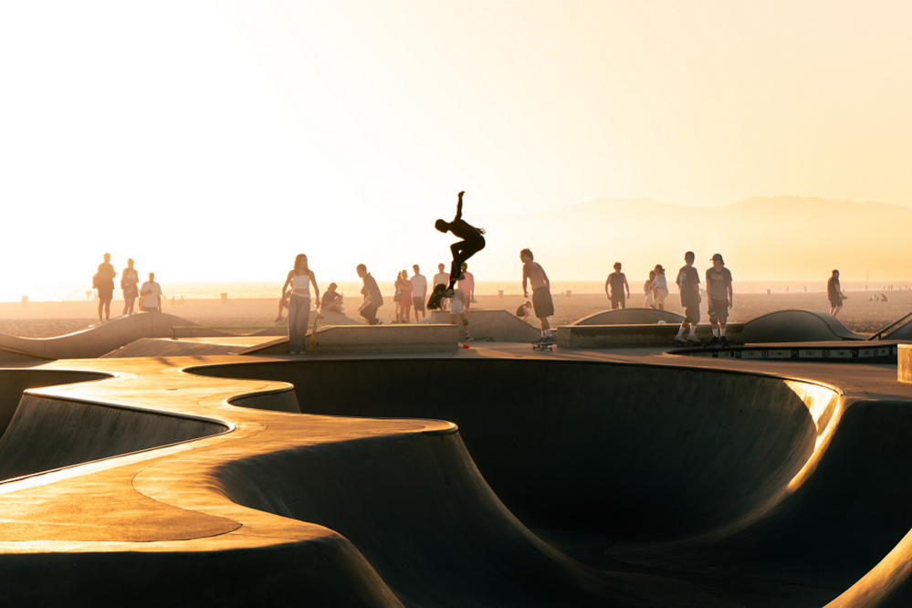 a skateboarder outlined against the warm sunset light in Venice Beach, Los Angeles, USA.