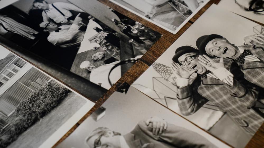 Several black-and-white photographs are laid out on a table