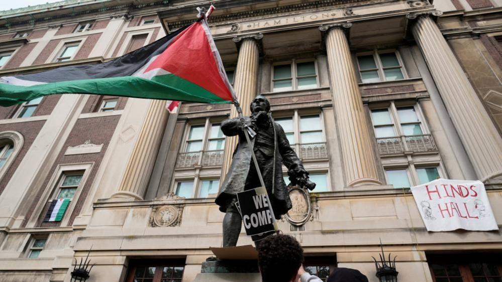 A student protester parades a Palestinian flag outside the entrance to Hamilton Hall on the campus of Columbia University, in New York, U.S., April 30, 2024.