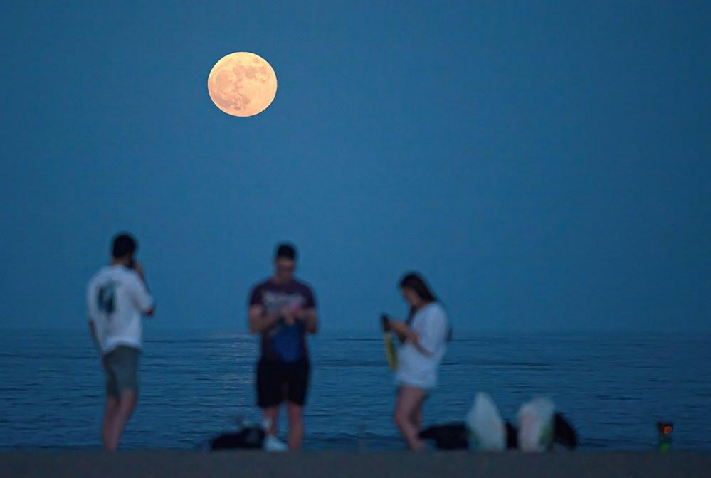 The full supermoon rising over Malagueta beach in Malaga