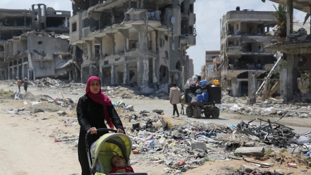 Palestinian woman pushes child in buggy in Jabalia (file photo)