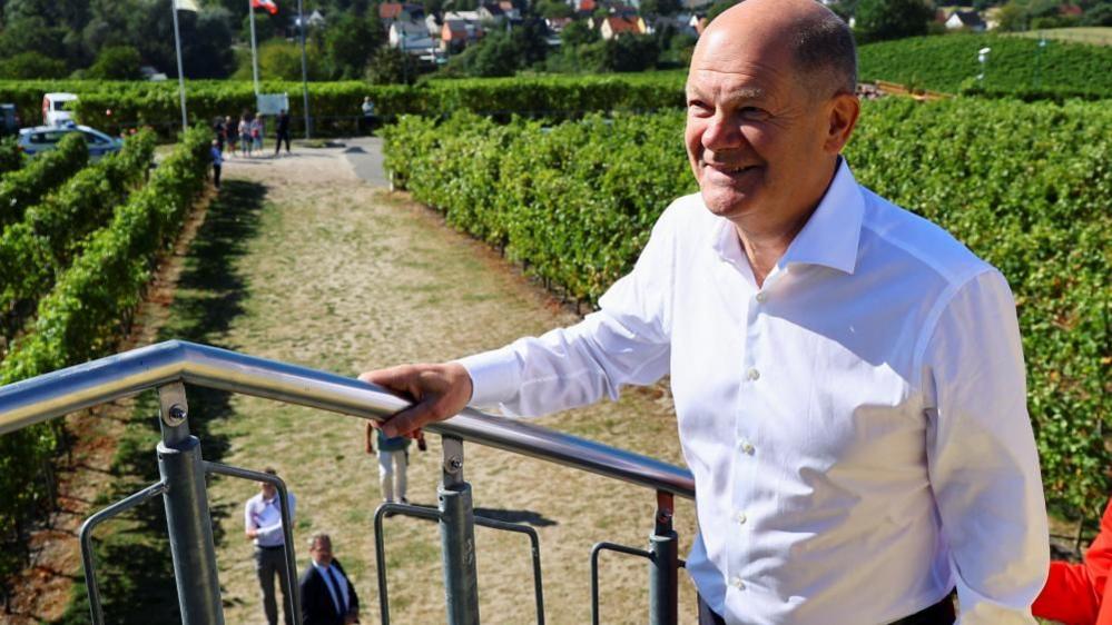 Man in white shirt walks up steps at vineyard